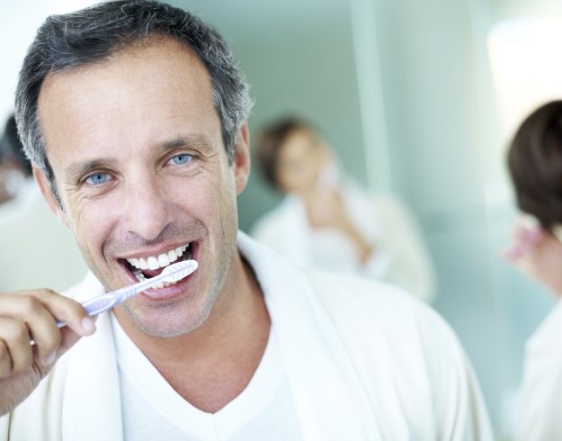 Man in white shirt brushing his teeth