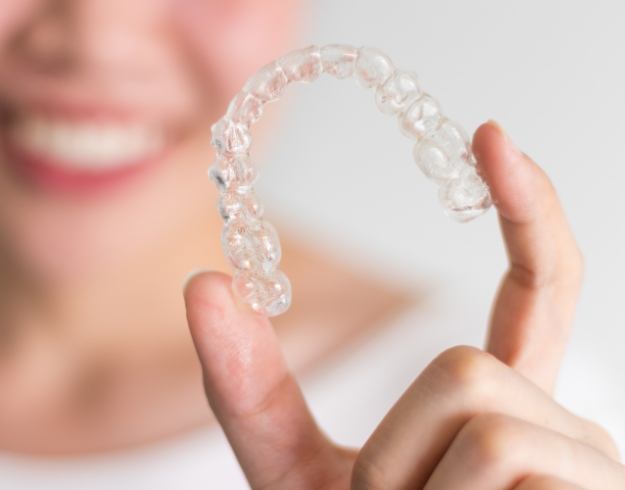 Hand holding a SureSmile clear aligner in Orlando