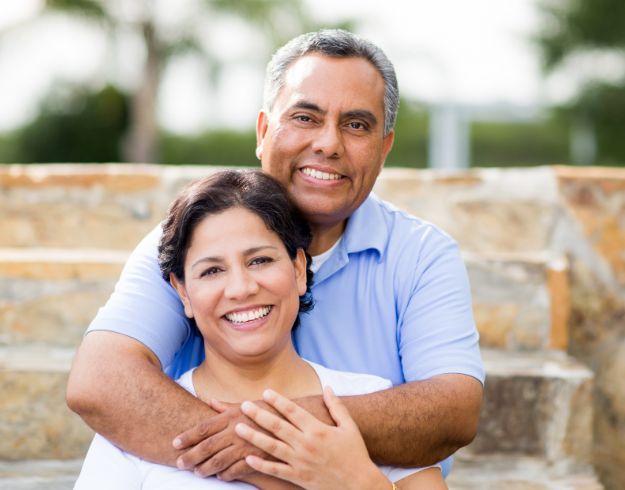 Man hugging woman from behind in front of brick wall