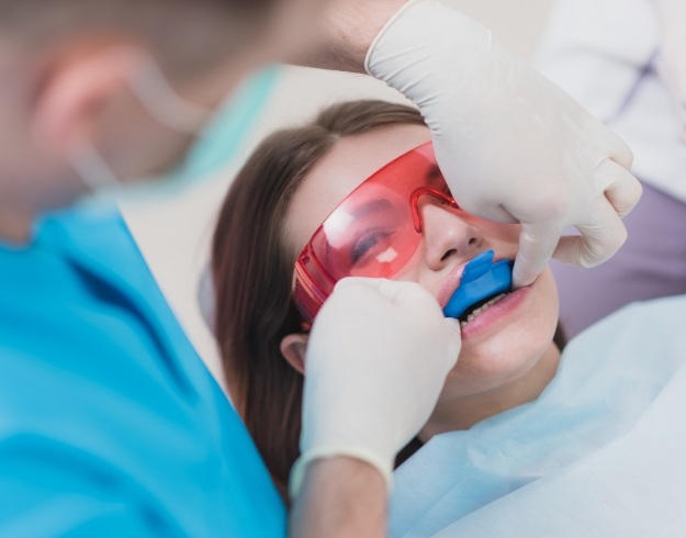 Young girl receiving fluoride treatment from dentist