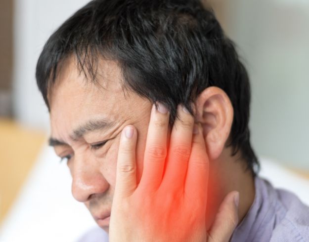 Man rubbing his jaw due to TMJ pain